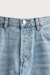 Pantalón jeans de corte recto, color celeste claro con efecto lavado, de cinco bolsillos y tiro medio.