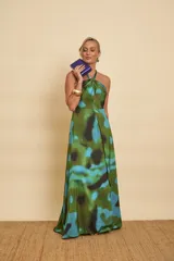 Vestido largo de satén con estampado abstracto en tonos verdes, azules y negros, escote halter y diseño fluido.