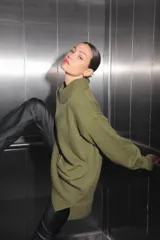 Sweater verde oliva de tejido de punto con cuello polo, mangas largas y corte oversize. Presenta un parche con monograma en la espalda.