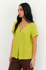 Blusa de lino color verde lima, con escote en V, mangas cortas y detalle de pliegue frontal.