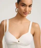 Top cropped blanco de tirantes anchos, confeccionado en tejido de punto texturizado, con escote en V y detalle de nudo o torcido en el centro del busto.