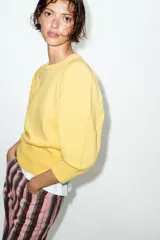 Jersey de punto color amarillo claro, con cuello redondo y mangas abullonadas.