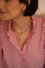 Camisa de corte clásico con estampado de rayas verticales rojas y blancas, cuello camisero con volados y cierre frontal de botones.