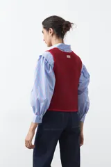 Chaleco de punto con efecto jaspeado en color azul, con diseño sin mangas, escote redondeado y cierre frontal mediante lazos ajustables.