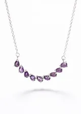 Collar de plata 925 con una hilera curva de piedras de amatista talladas en forma de gota. La cadena es de eslabones finos.