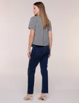 Blusa de manga corta con micro-estampado geométrico en blanco y negro, escote redondo con abertura tipo gota y lazo fino para atar.