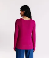 Suéter de punto color rosado, con cuello barco, mangas largas y puños con botones decorativos. El dobladillo también es acanalado.