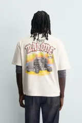 Camiseta de corte relajado color crudo, con cuello redondo y manga corta. Presenta un estampado gráfico pequeño en el pecho y un diseño grande en la espalda relacionado con el artista Post Malone.