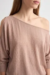 Blusa rosada de manga dolman larga, con escote asimétrico estilo hombro caído y detalle de abertura en la manga.