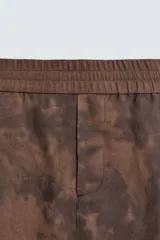 Bermuda estilo jogger de calce relajado, color marrón con efecto tie-dye. Posee cintura elástica ajustable con cordón y bolsillos delanteros y traseros de vivo.