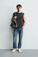 Musculosa de corte relajado en color negro con efecto lavado. Presenta cuello redondo, sisas amplias con acabado irregular y estampado gráfico de Jurassic Park en el frente y la espalda.