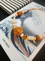 Collar de abalorios artesanal con cuentas de diferentes formas, tamaños y texturas en tonos tostados, marrones y blancos, destacando un dije central acanalado en tono ámbar con vetas blancas.