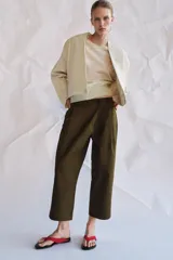 Pantalón cropped de tiro medio con diseño de pinzas en el delantero, trabillas para cinturón, bolsillos laterales y bolsillos de vivo en la parte trasera. Cierre frontal con cremallera y botón.
