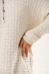 Buzo oversize color beige confeccionado en tejido sintético con destellos de lurex, cuello redondo y manga larga.