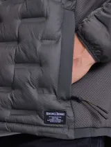 Campera de nylon termosellada con capucha, color azul marino, con cierre frontal y detalles en color naranja en el borde del cierre y costuras de la capucha.