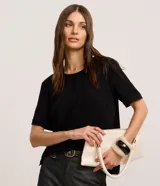 Blusa negra de manga corta con cuello redondo pespunteado, abertura tipo gota en la espalda y cierre de botón. Confeccionada en poliéster plano con efecto airflow.