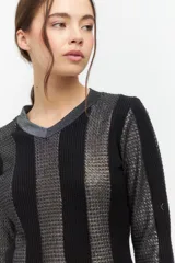 Blusa de manga larga con escote en V, confeccionada con un diseño de paneles verticales alternados en tejido negro liso y tejido calado con hilo metalizado plateado.