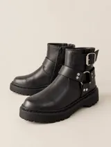 Botas de caña baja confeccionadas en cuero vacuno encerado color negro. Presentan un diseño con hebillas metálicas niqueladas en la caña y una tira decorativa con herrajes en el tobillo. Cuentan con cierre lateral, suela de goma negra con plataforma y forro interior de cuero vacuno.
