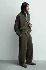 Zapatilla de cordones color verde militar, con parte superior de piel con acabado serraje y detalle de pespuntes en el empeine. Tiene horma redonda y suela plana de goma en color negro.