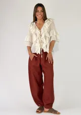 Pantalón bombacho de lino color marrón rojizo, con diseño a rayas sutiles, tiro alto y bolsillos laterales.