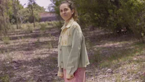 Chaqueta color beige con estampado abstracto en tonos amarillos, con cuello camisero, cierre frontal con botones, bolsillos plaqué y puños camiseros.