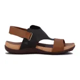 Sandalia plana de mujer color negro, con diseño cerrado en la parte delantera que cubre los dedos y parte del empeine con tiras cruzadas. Posee una pulsera ajustable con velcro en el tobillo. La suela es de goma marrón con plantilla color corcho.