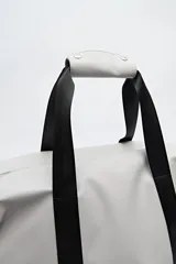 Bolso tipo duffel negro de símil cuero con cierre superior de cremallera metálica y asas reforzadas.