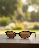 Lentes de sol con montura fina y estrecha de forma ovalada, color negro. Lentes de color marrón con protección UV400.