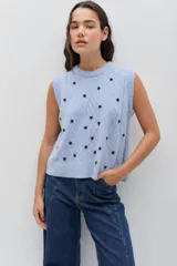 Chaleco de punto color celeste, con diseño de trenzas y pequeñas flores bordadas a mano en color marrón oscuro. Presenta cuello redondo y terminaciones acanaladas.