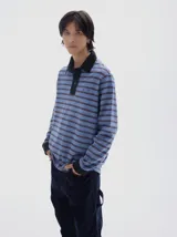 Chomba de manga larga con diseño de rayas horizontales en tonos azules y marrones, con efecto lavado. Presenta cuello polo y cartera de botones en color negro, además de puños negros y bordado pequeño en el pecho.