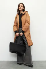 Campera de nylon larga oversized color negro, con capucha, tres bolsillos externos y uno interno. De tela capitoneada, con puños en las mangas y forro polar.