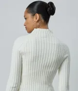 Blusa cropped de punto chenille color negro, con cuello alto y mangas largas raglán. Presenta una textura acanalada y pequeños puntos brillantes aplicados en el frente.