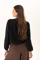 Chaleco negro con escote en V y cierre frontal mediante botones. Presenta un diseño versátil y moderno, ideal para usar solo o como capa sobre otras prendas.