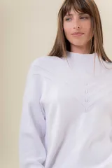 Sweater tejido de punto color blanco, con cuello alto y diseño en relieve tipo chevron en la parte frontal. Presenta un calce holgado con terminaciones acanaladas en puños y ruedo.