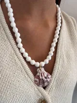 Chaleco de punto color crudo con escote en V y botones dorados.