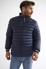 Campera puffer de nylon color azul marino, con cierre frontal completo, cuello alto y puños con detalle de rayas. Cuenta con bolsillos laterales con cierre y logo estampado en el pecho.