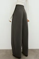 Pantalón balloon de tiro alto y diseño abuchonado, en color marrón oscuro con sutiles rayas verticales. Cuenta con pinzas y pliegues pronunciados en el delantero.