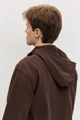 Buzo de friza de algodón marrón con capucha, cuello tipo polo con botones y un bolsillo frontal con solapa en el pecho.
