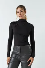 Body color visón con cuello tipo polera y mangas largas. Tiene frunces en los costados.