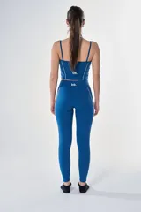 Conjunto deportivo compuesto por un top de tirantes finos con detalle de borde en contraste y calzas largas ajustadas, ambos en color azul petróleo.