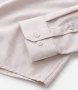 Camisa de manga larga confeccionada en tricolina de algodón, con cuello inglés, cierre frontal de botones y puños abotonados. Diseño liso y versátil.