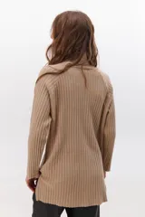 Polera de tejido de punto acanalado en color negro, con cuello alto y diseño de corte recto con largo asimétrico, más corto adelante y más largo atrás.