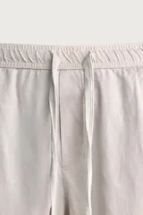 Pantalón de corte relajado confeccionado en una mezcla de algodón y lino. Presenta cintura elástica con cordón ajustable, bolsillos laterales y bolsillos traseros de vivo.