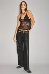 Pantalón de cuero ovino con corte oxford y tiro medio. Presenta diseño de cinco bolsillos, cierre frontal con botón metálico y costuras horizontales a la altura de la rodilla.