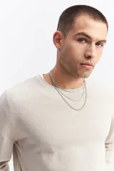 Sweater de algodón con textura acanalada, cuello redondo, mangas largas con hombros caídos y calce relajado. Presenta un logo bordado sutil en el pecho.