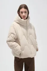 Campera puffer de cuello alto con capucha integrada, cierre frontal y diseño acolchado con costuras onduladas. Presenta mangas largas y bolsillos laterales.