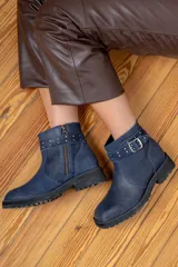 Bota corta de cuero azul con suela track negra, detalle de tira con hebilla metálica y tachas decorativas en el tobillo.