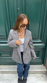 Blazer gris con solapas de muesca, bolsillos con solapa en el frente y un botón de cierre.