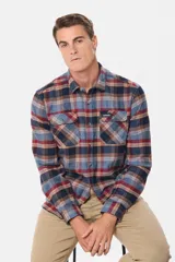 Sobrecamisa de viyela gruesa con diseño de cuadros en tonos azul y bordó. Cuenta con cuello clásico, cierre frontal con botones y dos bolsillos delanteros con solapa y botón.