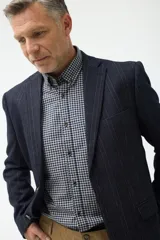 Blazer de corte clásico en color azul marino con patrón de cuadros sutiles. Presenta cierre frontal de un botón, solapas de muesca y bolsillos laterales con solapa.